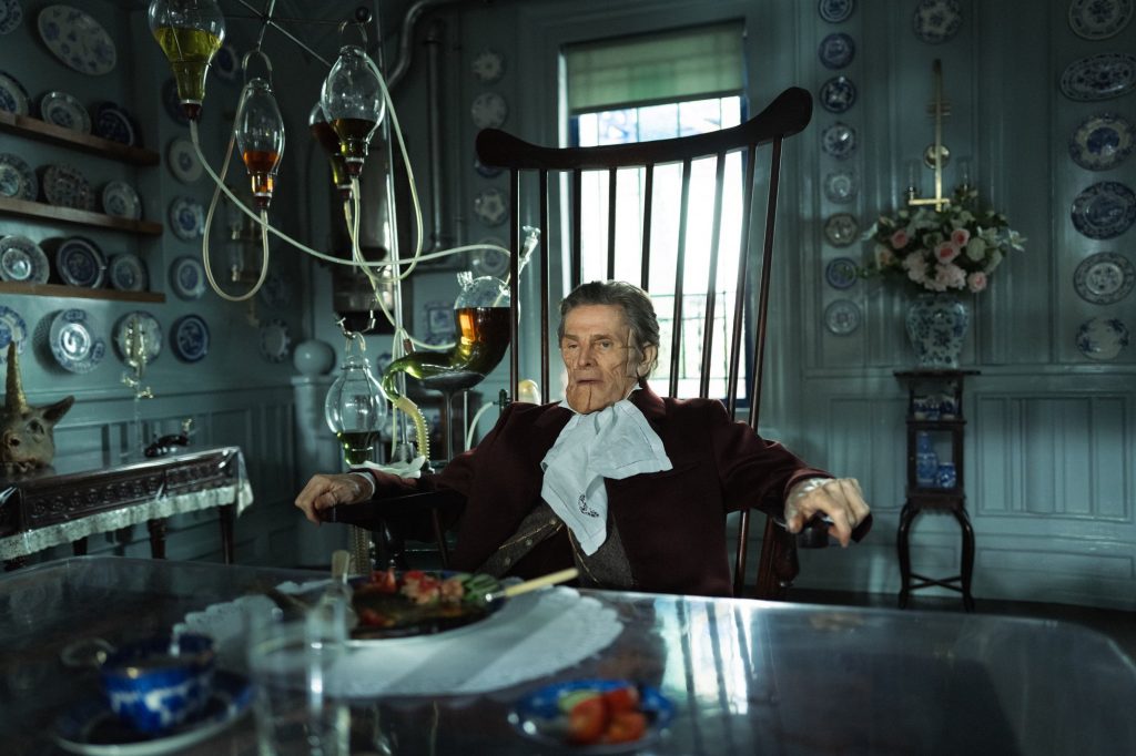 Godwin Baxter (Willem Dafoe) attablé dans son manoir londonien, le visage abîmé et rapiécé - Photo by Yorgos Lanthimos - Courtesy of Searchlight Pictures - © 2023 Searchlight Pictures All Rights Reserved.